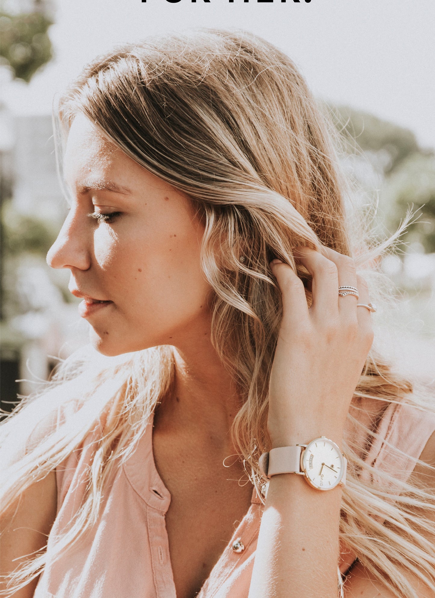 woman in a sunlit area brushing back her hair. She has an Arvo Awristacrat watch on her wrist