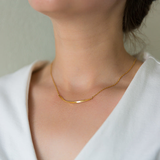 Woman wearing a gold twisted bar necklace