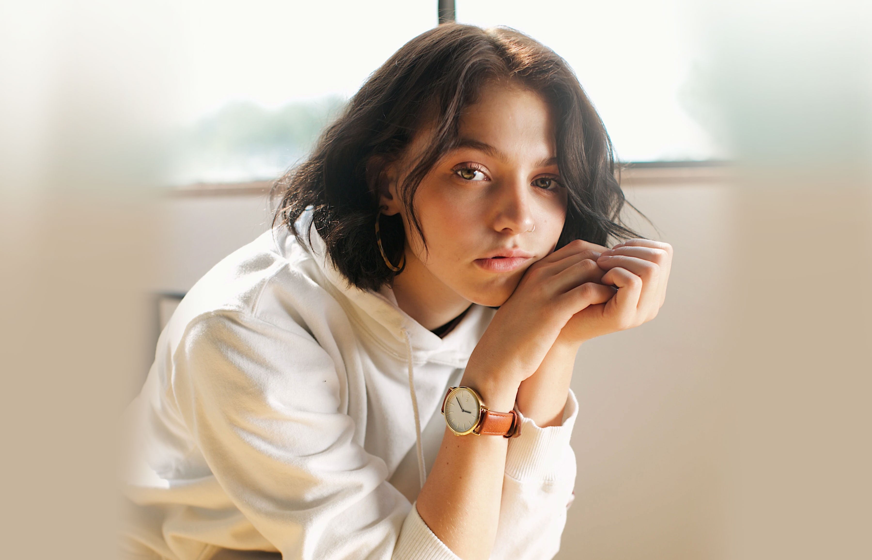 Young Woman wearing one of the Arvo Time Sawyer watches for women and men. Watch has a white dial, gold case, and brown leather watch band strap