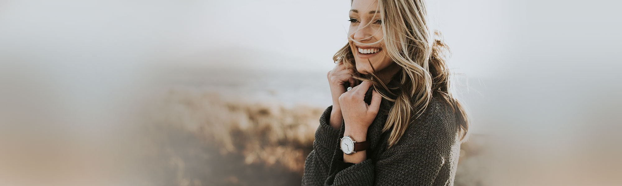 Woman outdoors dressed in a brown sweater wearing an Arvo Time Sawyer Watch with a white dial, silver case, and a brown stitched watch band.