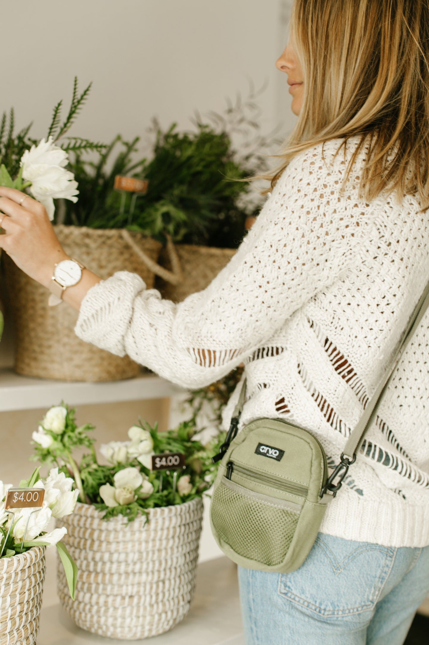 woman shopping for flowers wearing an Arvo Fanny canvas crossbody bags for women in a willow green color