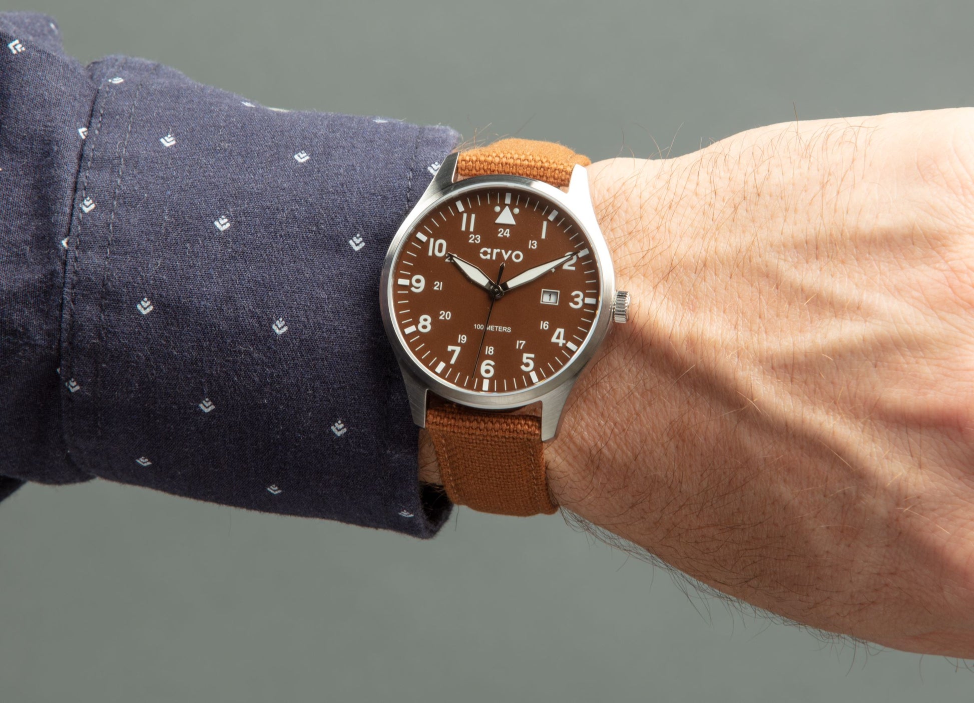 Wrist shot of  the Arvo Rove Field Watch for men with a buckeye brown dial and brown canvas strap