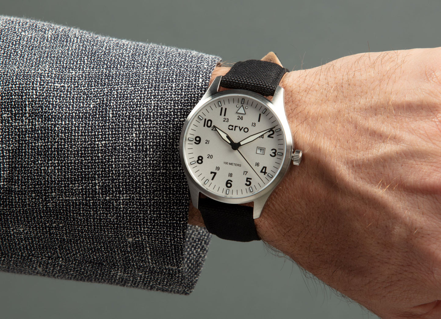 Wrist wearing an Arvo Rove Field Watch for men with a moon white dial and black canvas strap