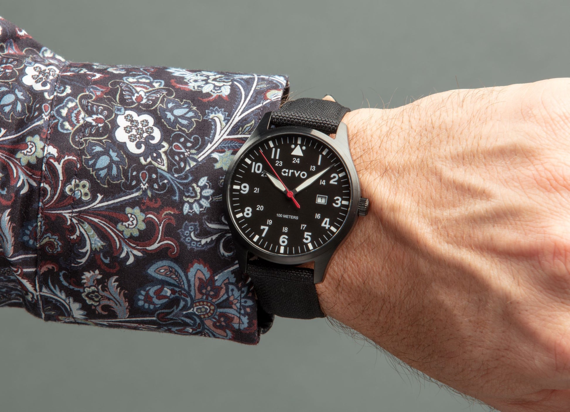 Man's wrist wearing an Arvo Rove Field Watch for men with a sky black dial and black canvas strap