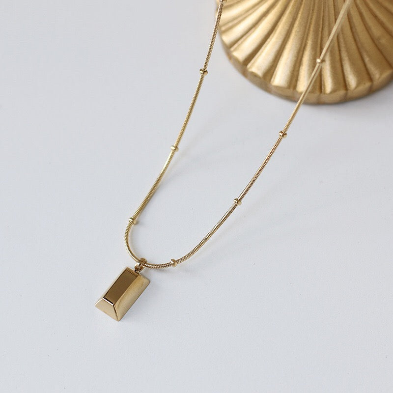 closeup of an Arvo gold brick on a gold chain necklace