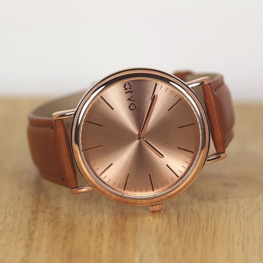 Arvo Rose Time Sawyer Watch for men and women with rose gold dial and rose gold case with a brown stitched leather band laying on a brown desktop