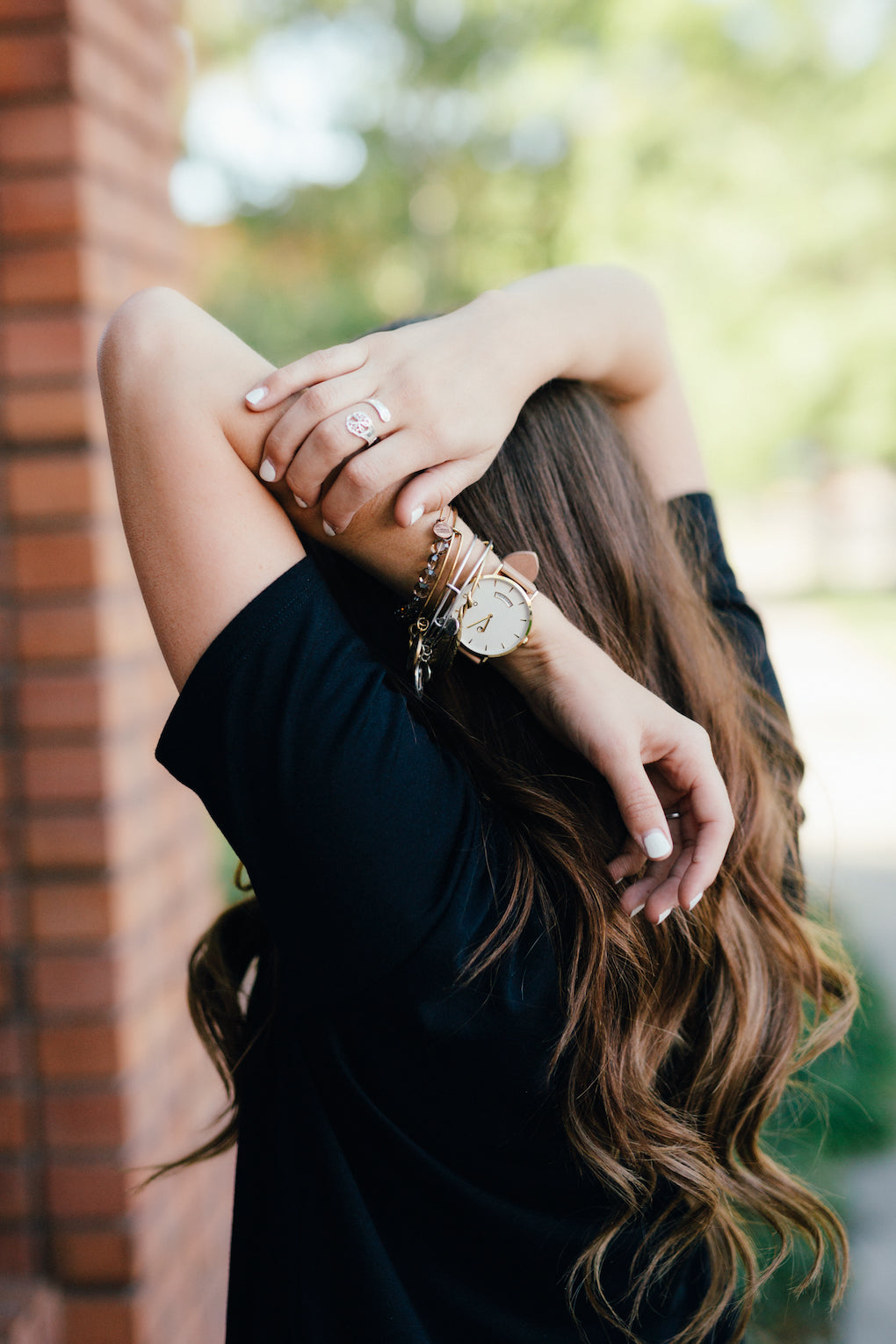 Woman with long brown hair and arms upstretched. She is wearing an Arvo Awristacrat gold watches for women with white dial, gold case, and nude or tan leather band