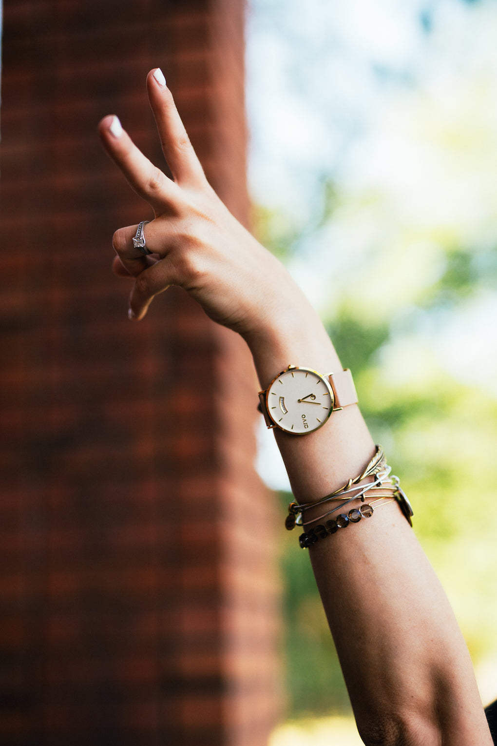 woman's arm up in the air. she is wearing an Arvo wrist watch and stack bracelets