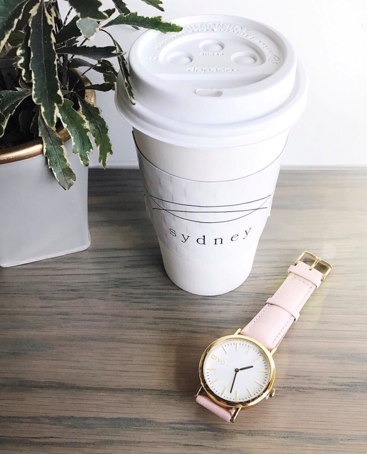 White Time Sawyer watch for women with a pink leather band on a table next to a white styro foam coffee cup