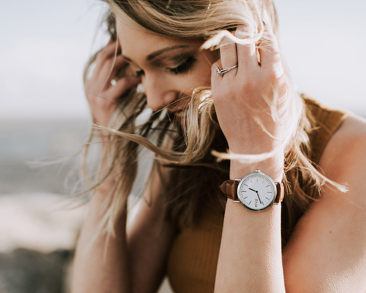 Woman on a beach wearing a Time Sawyer Watch for men and women with white dial, silver case and brown leather band