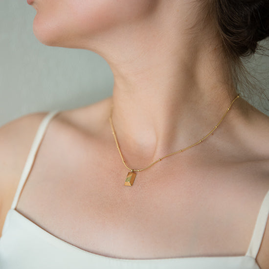 woman modeling an Arvo gold brick on a gold chain necklace